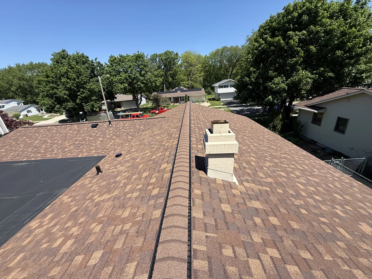 Brown shingle roof running up to a chimney