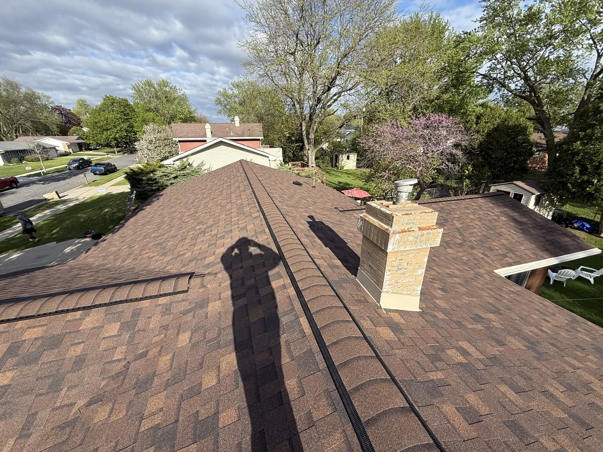 Brown shingle roof around a brick chimney