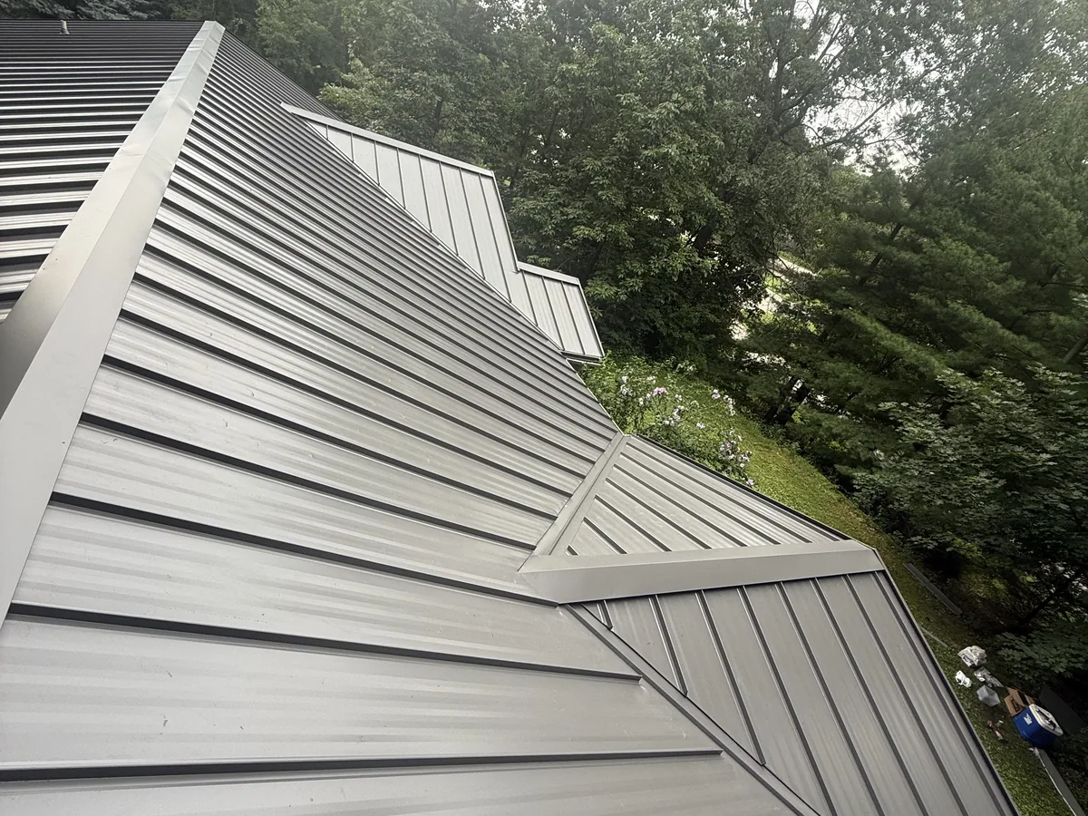 Tan metal roof panels meeting at a hip and valley